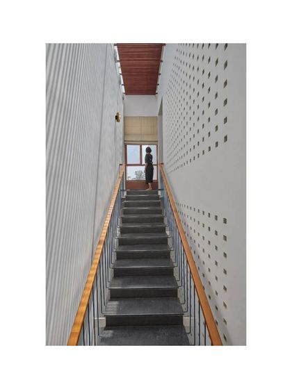This narrow staircase in the Vikas Residence is flanked by a perforated wall that creates a pattern of light dots. It's a simple detail that adds a layer of texture and visual interest to the space.