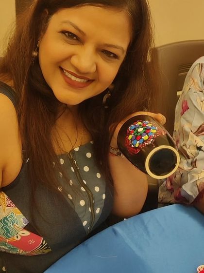 A happy participant from the Sakhi Ladies Group showing her unique, colorful dot art mug.