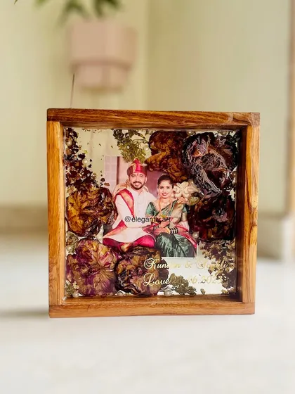 Another view of a beautiful teakwood frame preserving a wedding garland. The flowers are artfully arranged, and the couple's names are inscribed, making it a perfect, personalized keepsake.