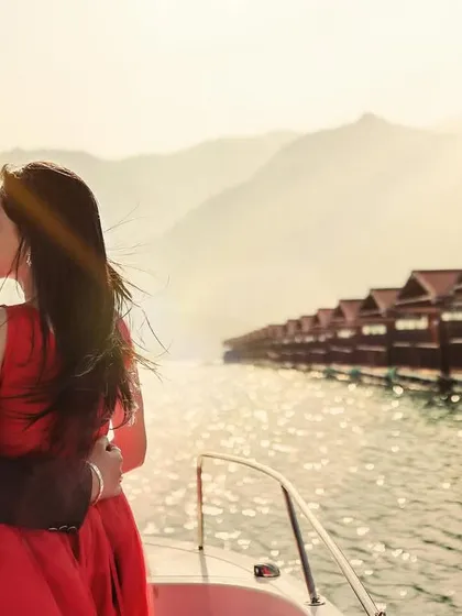 A beautiful backlit shot of a couple on a boat at sunset. The golden light and the sparkling water create a magical and romantic atmosphere.