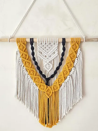 This custom-ordered, three-layered macrame wall hanging showcases our intricate knotting work. We combined off-white, black, and mustard yellow threads to create a striking boho design that adds texture and personality to any wall.