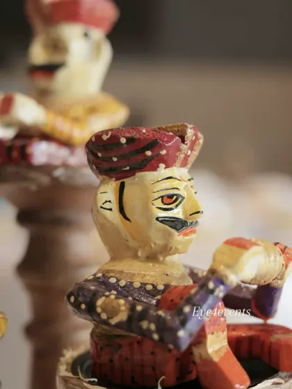 A detailed macro shot of one of the hand painted wooden musician figurines. These small, artistic touches add a layer of authenticity and charm to culturally themed event decor.