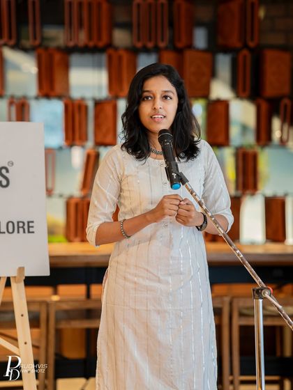 A performer stands confidently at the mic, her hands clasped as she delivers her poem. This shot captures the courage and passion of our community's spoken word artists.
