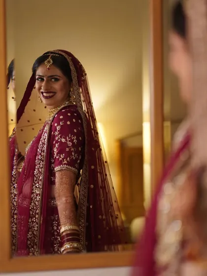 A classic bridal portrait, with the bride looking at her reflection in the mirror, capturing a moment of quiet anticipation.