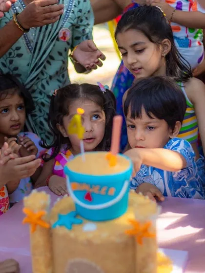 The kids' faces say it all! They are completely mesmerized by the sandcastle cake at this beach party.