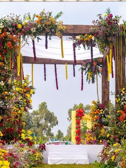 The garden mandap seen through an aisle of flowers, creating a sense of wonder and anticipation for the wedding ceremony.