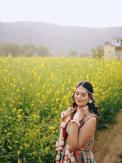 A dreamy shot in a field of yellow flowers, perfectly matching the Haldi theme. Her makeup is kept soft and romantic.