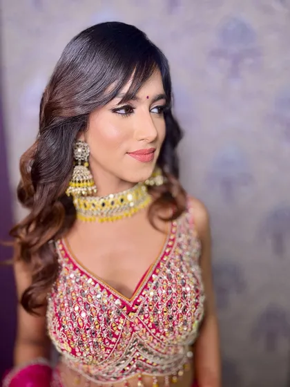 A beautiful side profile, highlighting the soft waves in her hair and the flawless finish of her makeup.