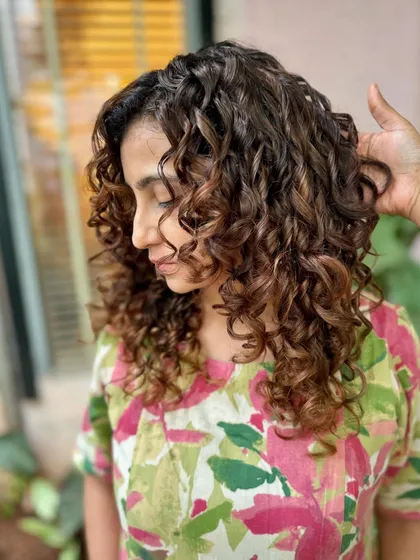 A side view of the 'Chocolate Swirl' curly transformation. The cut and color work together to create a beautiful shape.