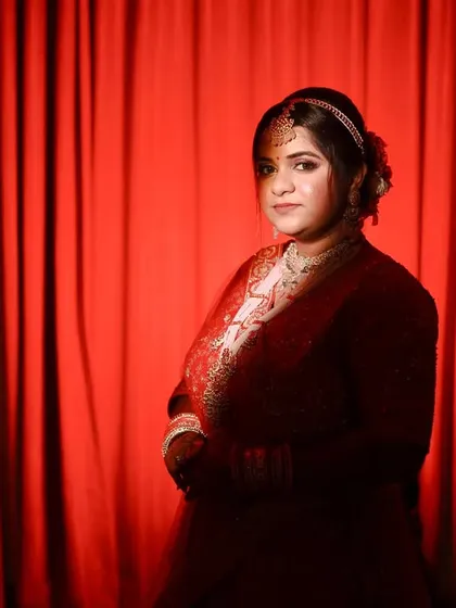 A striking bridal portrait against a red curtain. The bold color and lighting create a dramatic, almost theatrical feel.