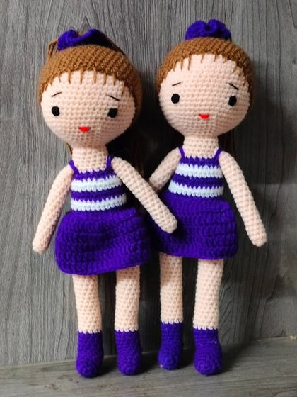 Two dolls in matching purple and white striped dresses. They look like twins.