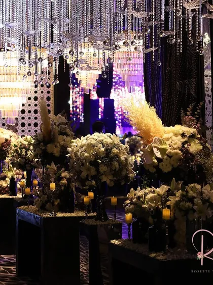 An entrance lined with white floral arrangements and candles, under a ceiling of hanging crystals. The design creates a sense of depth and luxury.