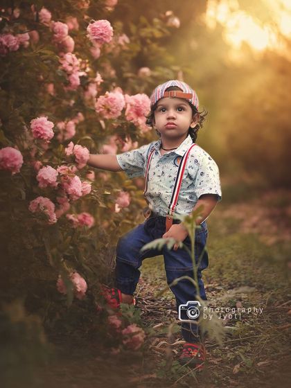 A charming outdoor portrait of a little boy interacting with a bush of pink roses. I encourage kids to explore their surroundings, which leads to natural and candid photographs.