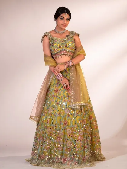 A full-length shot of the green floral lehenga, styled with a bun and traditional jewelry for a complete desi look.