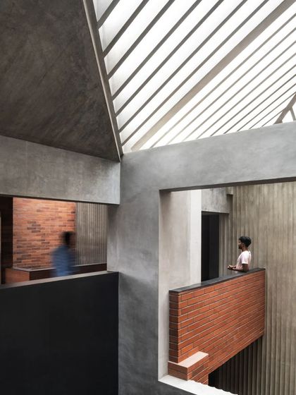 A view across the void in the Brick House, where human figures animate the architectural composition of light, shadow, and texture.