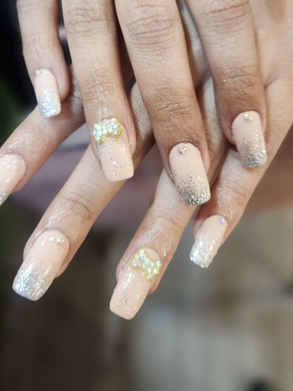 This elegant set features a nude-to-silver glitter ombre on long, square nails. The look is completed with charming 3D bow embellishments made of tiny pearls.