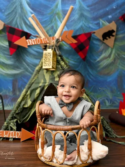 A big, happy smile from our little camper. The "Into the Wild" theme is brought to life with a teepee, a felt campfire, and forest-themed banners.