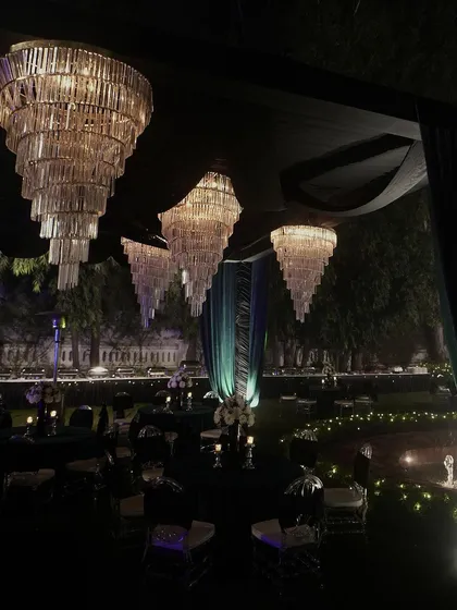 A breathtaking view of the Sangeet venue, with dozens of tiered chandeliers creating a forest of light under a canopy of dark teal fabric.