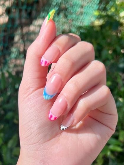 A close-up showing the detail of the multi-colored French tips, with each nail featuring a different abstract color blend.