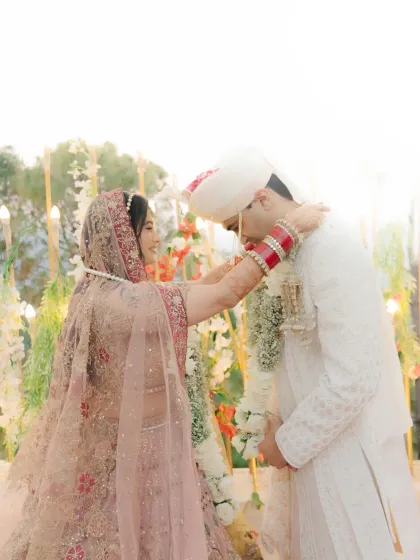 The bride places the garland on the groom, a moment of love and tradition captured in beautiful, soft light.