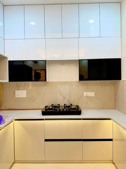 A completed U-shaped modular kitchen in white high-gloss finish at Saviour Greenarch, offering plenty of counter space and storage.