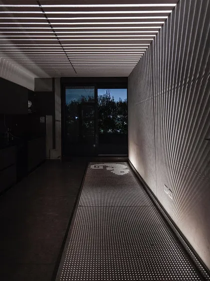A duplicate of the previous image, this shot emphasizes the transformative effect of light in our studio. The perforated steel walkway creates a "diaphanous connection" between floors while casting dynamic shadows.