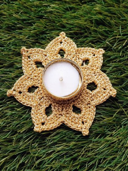 A top-down shot of the golden tea light holder on a green background, highlighting the intricate, flower-like pattern.
