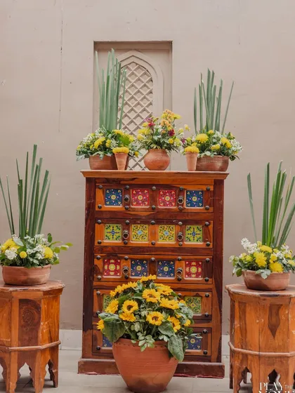 A beautiful decor detail from a Haldi ceremony, featuring a rustic wooden cabinet adorned with sunflowers and traditional pottery.