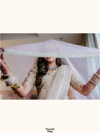 A mysterious and artistic bridal portrait, with the bride's face partially hidden by her delicate, sparkling veil.