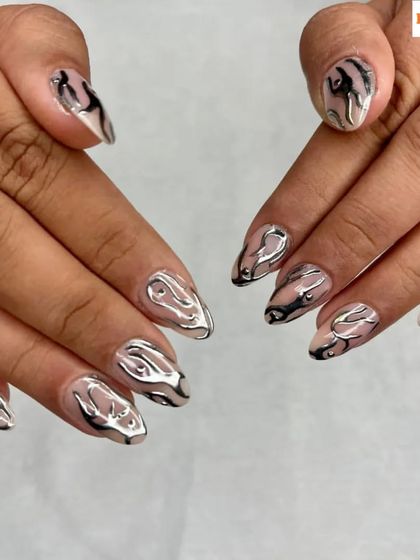 A futuristic and edgy design. These almond-shaped nails feature a clear base with 3D liquid silver chrome art, creating a stunning, abstract metallic effect.