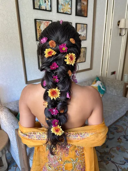 There's nothing like fresh flowers to bring a hairstyle to life. This voluminous, messy braid for a Haldi ceremony is adorned with vibrant, colorful flowers, creating a look that is joyful, festive, and perfectly in tune with the celebration.