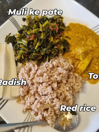 This is a traditional and balanced Indian meal. It features red rice, which is higher in fiber than white rice, alongside tofu curry for protein, and a side of radish greens (muli ke patte) and fresh radish. It's a great example of a wholesome, plant-based plate.