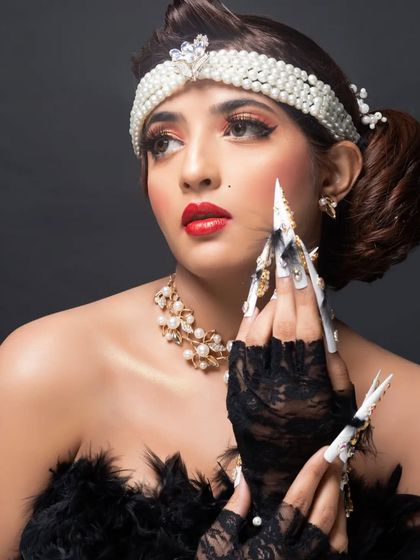 A close-up of the model's hands, highlighting the showstopping fantasy nail art and its glamorous, over-the-top style.