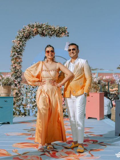 The couple poses with style at their carnival-themed Mehendi event, their modern outfits perfectly matching the vibrant decor.