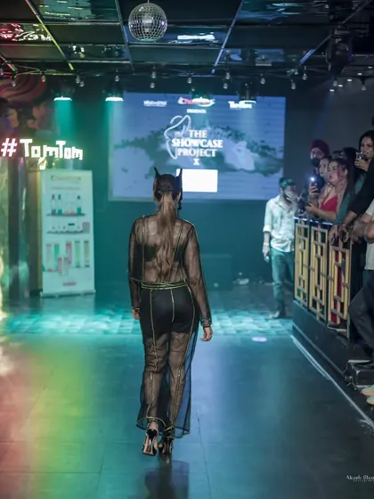 A shot from behind, showcasing the sheer back of the outfit and the model's confident exit from the runway.