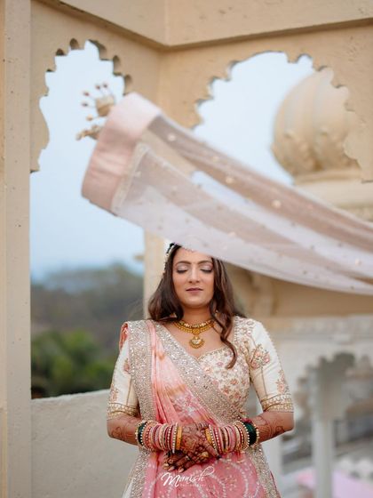 A serene bridal portrait, with the bride's veil gently blowing in the wind against the backdrop of arched windows.