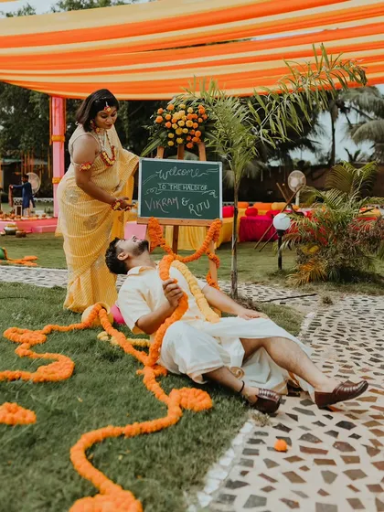 A playful shot of the couple with a welcome sign at their Haldi ceremony.