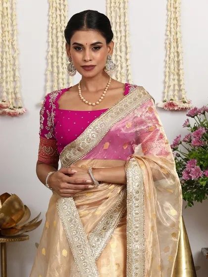 A close-up of the embroidered pink blouse, contrasting beautifully with the gold saree.