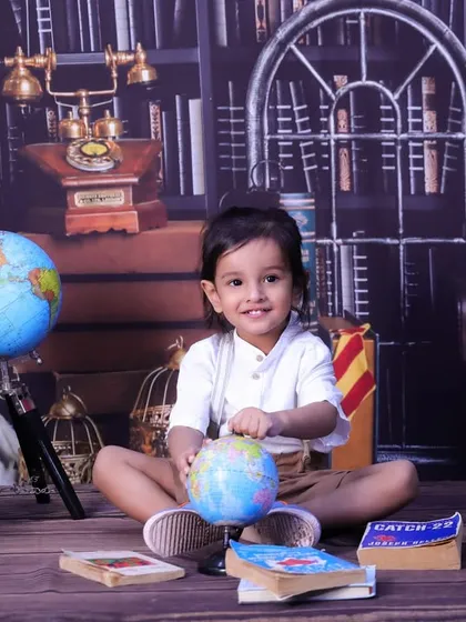 A little explorer with a globe in our library theme. This shot combines a love for adventure and stories, perfect for a curious toddler.