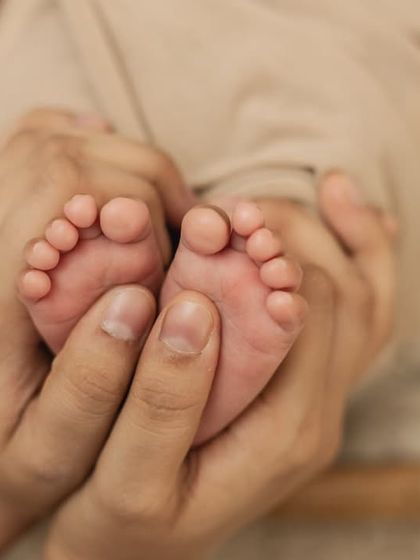 A mother's hands holding her baby's feet, a tender and loving detail shot.