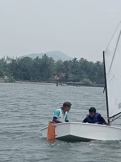 An instructor provides guidance to a young sailor as they navigate the waters of Karwar.