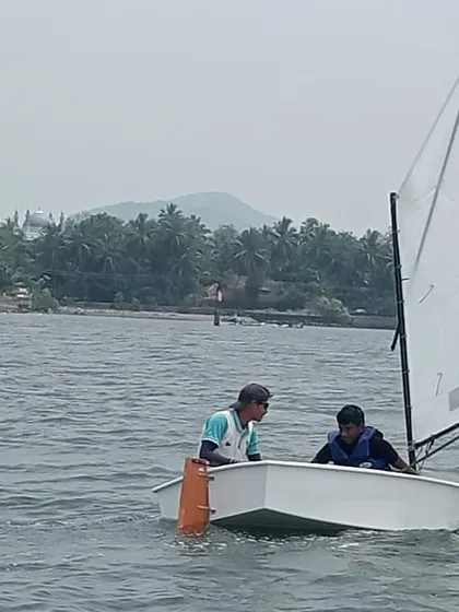 An instructor provides guidance to a young sailor as they navigate the waters of Karwar.