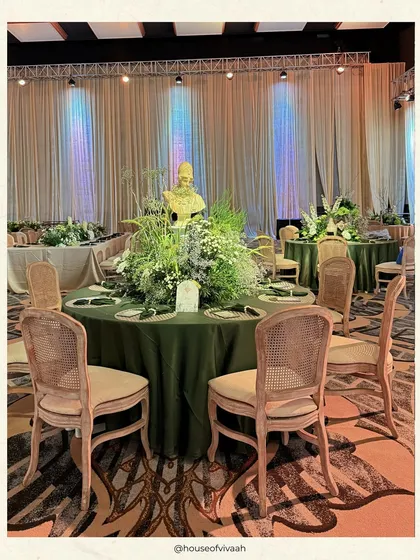An elegant dining setup with cane-back chairs, an olive green tablecloth, and a lush baby's breath centerpiece, creating a look that is both rustic and refined.