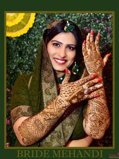 A classic Mehndi portrait where the bride displays her fully decorated hands and arms.