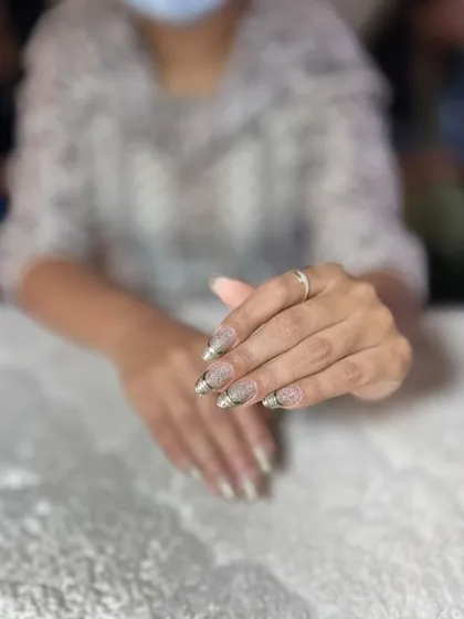 A glittery gold French tip on a nude base. This is a glamorous and festive look perfect for any party.