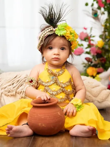 This little Radha looks so sweet and thoughtful with her pot of butter. The details in her outfit and the surrounding decor make the theme come alive.