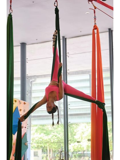 An advanced student performs a perfect split on the silks, demonstrating incredible flexibility and control high above the ground.