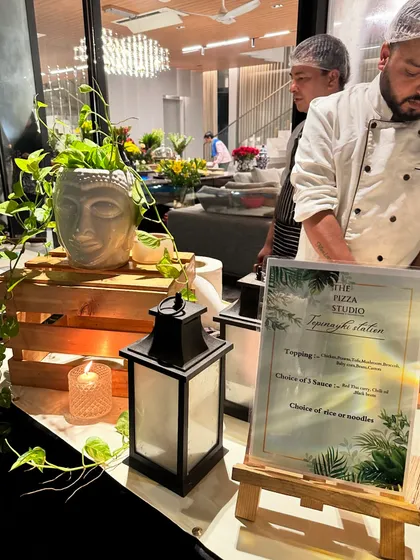 Our Teppanyaki station is designed to blend seamlessly with your event's decor. Here, it's styled with a Buddha head planter and lanterns, showing how we customize our setups to fit the party's theme.
