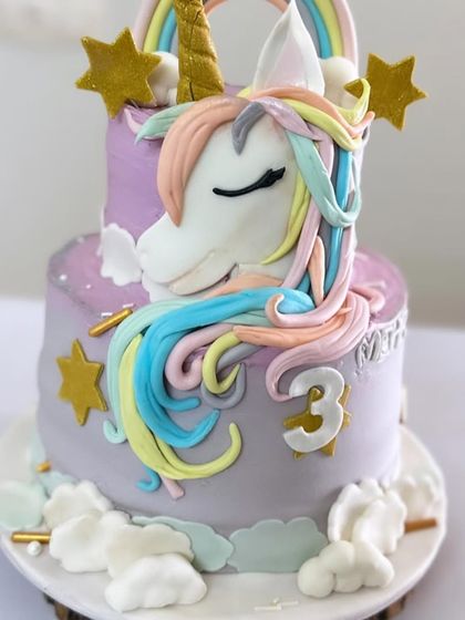 A full view of the magical unicorn cake, showing both tiers and the dreamy cloud-like buttercream at the base.