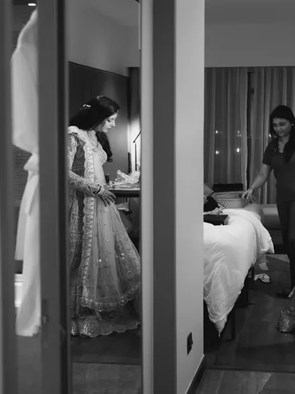A candid black and white shot of the bride getting help with her outfit.